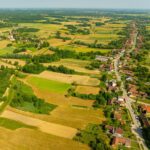Aerial view of rural land, farmland, roads, and nearby homes for remote land buyers