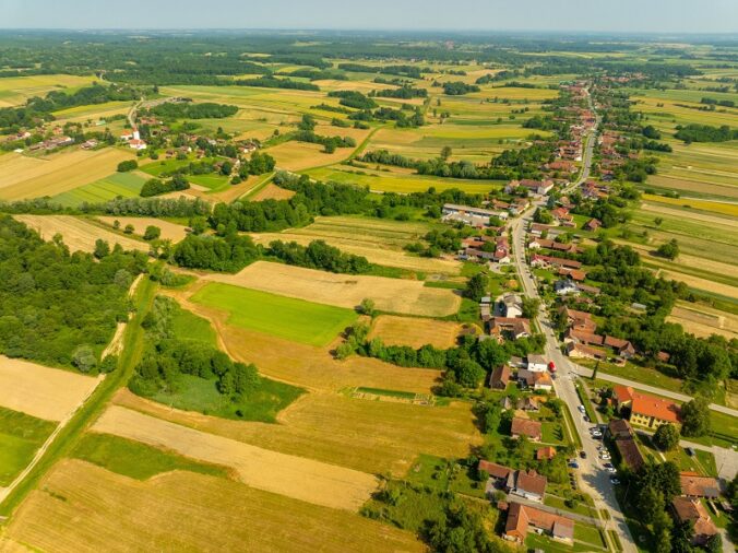 Aerial view of rural land, farmland, roads, and nearby homes for remote land buyers
