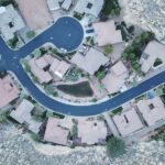 Aerial view of residential land development with homes, roads, landscaping, and rocky terrain