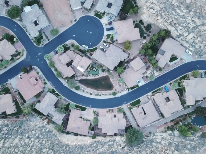 Aerial view of residential land development with homes, roads, landscaping, and rocky terrain